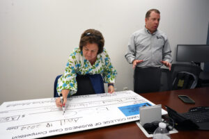 UMW business alum and successful businesswoman Linda Blakemore '84 pens the check to the winners of the College of Business Case Competition. Students Jenna Diehl and Brian Gaydos received $3,500. Photo by Suzanne Carr Rossi.