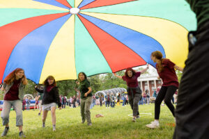 Students tunnel beneath a multi-colored parachute during Devil-Goat Day.