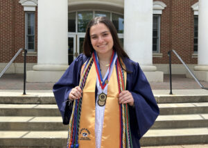 Senior Madeline Brunt poses in her graduation gown in front of the Jepson Science Center. Scholarships helped Brunt, who majored in biological sciences and minored in ethics, engage in undergraduate research, study abroad in the Galápagos Islands and serve as president of UMW's Performing Arts Company. Photo courtesy of Madeline Brunt.