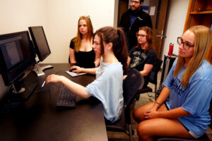 Assistant Professor of Psychological Science Marcus Leppanen (standing) watches while (from left to right) UMW psychology majors Kelly Simons, Julia Patrick, Tobias Conner and Brianna Daly look at results of their research working with the Tobii Pro Fusion Eye Tracker. The team tracked eye-movements during test-taking. Photo by Suzanne Carr Rossi.