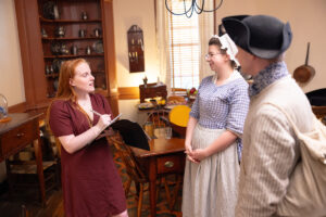 Intern Claire Feil with the Washington Heritage Museum standing with historical re-enactors inside the Rising Sun Tavern. 