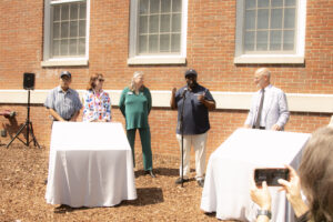 A group poses before the two Fredericksburg Civil Rights Trail markers located at UMW's Combs Hall are unveiled. Pictured from left to right are: Frank White, Fredericksburg Mayor Kerry Devine, City of Fredericksburg Tourism Stadium and Sales Manager Victoria Matthews, UMW James Farmer Multicultural Center Assistant Director Chris Williams, UMW President Troy Paino. Photo by Karen Pearlman.