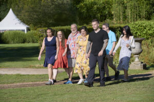 Jenn Reyes '99 (far left) walks onto the set with fellow contestants during the first episode of season two of 'The Great American Baking Show.' During 'Cake Week,' Reyes baked a confection recalling the classic cartoon 'The Smurfs.' 'I hope I can smurfin’ finish this in smurfin’ time,' she says on the show.