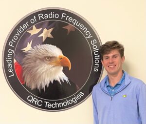 Senior William Thompson poses with QRC Technologies background, where he is completing his summer internship. 