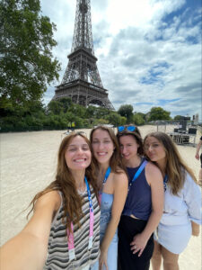 Hadley Mantia '24 (front) snaps a selfie near the Eiffel Tower in Paris. Mantia, who majored in international business and French at UMW, is using her fluency to meet and greet Olympics spectators from around the world as a bus host for sponsor Allianz.