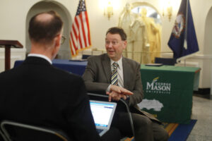 UMW College of Arts and Sciences Dean Keith Mellinger talks to a George Mason University administrator at the signing. The agreement permits dual enrollment, allowing UMW students to combine undergraduate and graduate degree requirements, reducing the time it takes to earn a master’s degree and unlock increased earning potential. Photo by Karen Pearlman.