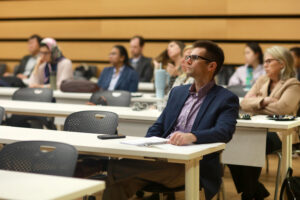 College of Business (COB) Associate Dean Christopher Garcia (front) listens to presenters during the Case Competition. COB Dean Filiz Tabak (far right) sits behind him. Photo by Karen Pearlman.