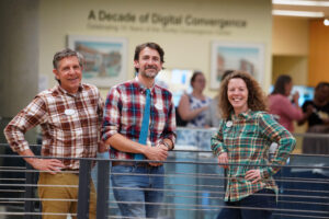 From left to right: Director of Digital Learning Support Jerry Slezak, along with Digital Knowledge Center Director Cartland Berge and Associate Director Shannon Hauser, pose for a photo during the opening reception for the 'A Decade of Digital Convergence' exhibit. The three lead the Hurley Convergence Center, now celebrating its 10th anniversary. Photo by Suzanne Carr Rossi.