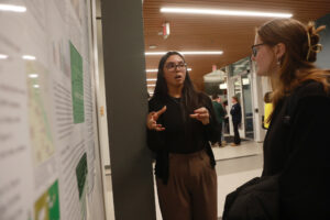 UMW senior Juliana Ramirez presents a poster summarizing her research on campus plant life to a passerby during the recent fall research symposium, held in Jepson Science Center. The event was one of several that allowed students to show off a semester's worth of work. Photo by Karen Pearlman.