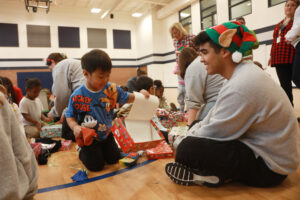 Each gift box contained essentials like hats, gloves, toothbrushes and toothpaste, as well as toys and art supplies to brighten the holidays for preschoolers, pictured with UMW student Matthew Cabrera '27. Photo by Karen Pearlman.