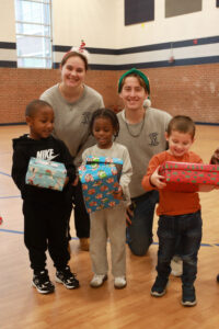 UMW junior Knox McKinley and sophomore Emily Helpinstill pose with children at Fredericksburg Walker-Grant Center this week during Mary Washington's annual gift box drive. Photo by Karen Pearlman.