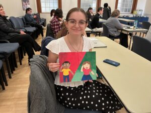 UMW senior Maria Werner, an elementary education major, poses with a sample of artwork included in a children's book she wrote to address ARFID, a condition that causes kids to avoid certain foods. Werner presented the research and process behind the book during the Honors Senior Capstone Fall Symposium, held in Lee Hall.