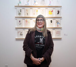 Garmon stands in front of the drawings she crafted for each featured artist – available for them to take home at the end of the show.